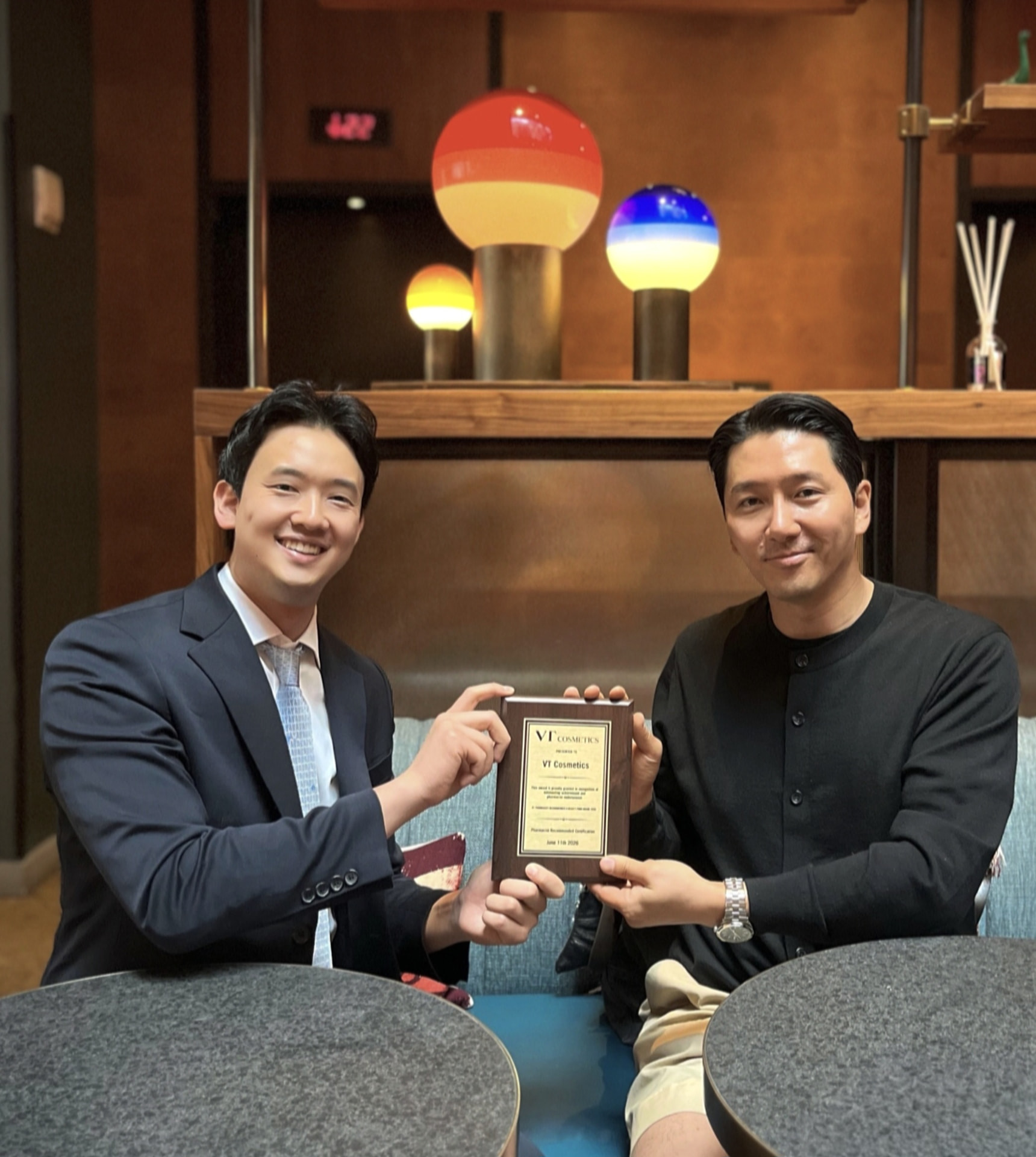 Two people holding the VT Cosmetics recognition plaque at an award presentation