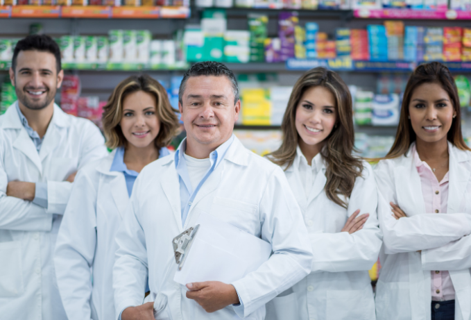 Team of five pharmacists in white coats at a pharmacy